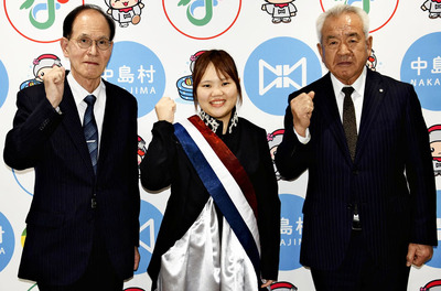 加藤村長（右）から激励金を受け、活躍を誓う西條さん（中央）。左は面川教育長