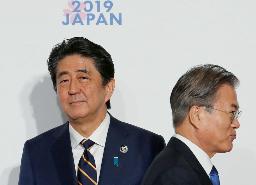 　Ｇ２０大阪サミットで握手した後、すれ違う韓国の文在寅大統領（右）と安倍首相（当時）＝２０１９年６月、大阪市（ロイター＝共同）