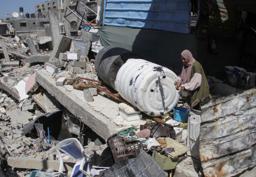 　イスラエルの攻撃で破壊された建物のがれきの上に立つ女性＝１２日、パレスチナ自治区ガザ北部ベイトラヒヤ（ロイター＝共同）