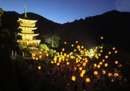 　世界遺産登録２０年を記念し、ライトアップされた「那智の滝」と三重塔の前で空中に浮かべられたＬＥＤランタン＝６日夜、和歌山県那智勝浦町