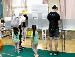 　東京都知事選で投票用紙に記入する有権者ら＝７日午前、東京都港区