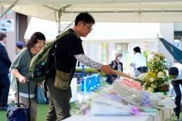 　安倍元首相銃撃事件から２年となり、奈良市の現場付近に設置された献花台に花を手向ける人たち＝８日午前