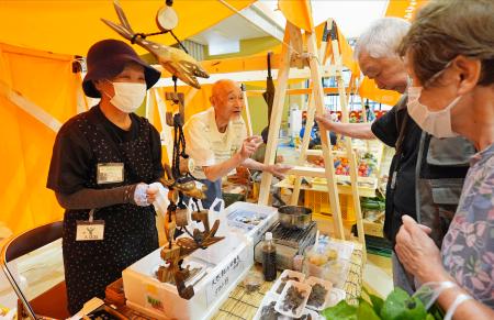 　石川県輪島市内の商業施設で出張開催された輪島朝市で、川魚料理を販売する福谷春夫さん（左奥）と和子さん（同手前）夫妻＝１０日午前