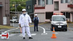 　男性が殺害された商店の近くを交通規制する警察官＝１０日、和歌山県海南市