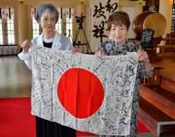 　返還された岡部辰美さんの日章旗を掲げる長女の芙佐子さん（右）ら遺族＝１４日、大阪市