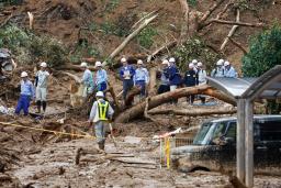 　松山市の土砂崩れ現場を視察する国交省の緊急災害対策派遣隊ら＝１４日午後