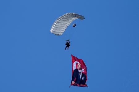 　トルコ軍の軍事侵攻５０周年記念式典の軍事パレードの上空で初代大統領ケマル・アタチュルクの肖像画とともに降下するパラシュート＝２０日、ニコシア（ＡＰ＝共同）