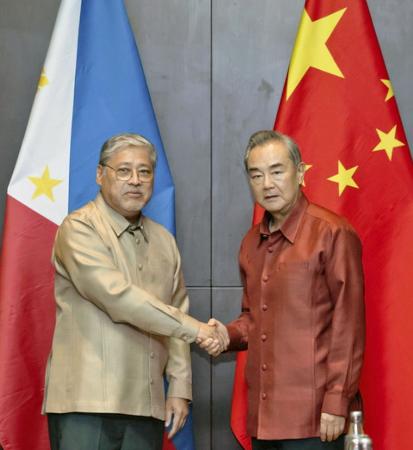　フィリピンのマナロ外相（左）と握手する中国の王毅外相＝２６日、ビエンチャン（中国外務省のホームページから、共同）