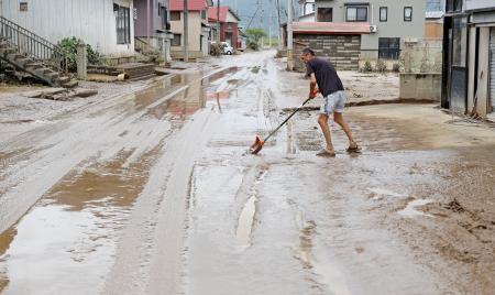 　山形県戸沢村の蔵岡地区で泥をかき出す長沢修さん＝２８日午前１１時２分