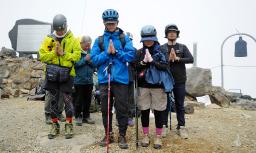 　御嶽山の頂上で手を合わせて黙とうする遺族ら＝２８日午前１１時５２分