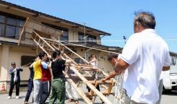 　能登半島地震で被災した石川県輪島市町野町で、祭りに向けて巨大な灯籠「キリコ」を準備する住民や学生ら＝６日午前