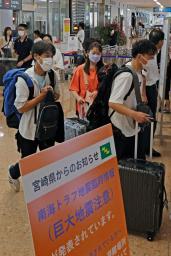 　宮崎空港に到着した人たち。ゲート前には南海トラフ地震臨時情報に関する看板が設置されていた＝１０日午前