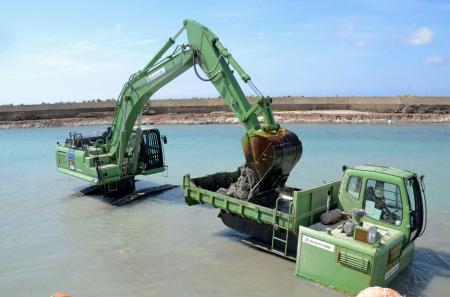 　能登半島地震で海底が隆起した石川県輪島市の赤神漁港で、土砂をさらう「しゅんせつ」作業を行う水陸両用のショベルカー（左）とダンプカー＝５日