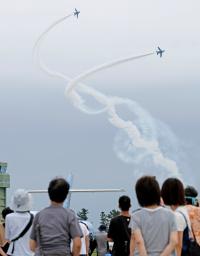 　航空自衛隊松島基地の航空祭で、アクロバット飛行を披露する「ブルーインパルス」と訪れた観客＝２５日午後、宮城県東松島市