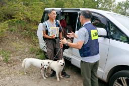 　北海道駒ケ岳で登山者（左）に噴火情報に関するパンフレットを配布する協議会の関係者＝２６日午前