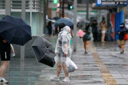 　傘を風であおられる人＝２９日午後３時１３分、ＪＲ博多駅前