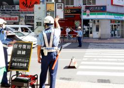 　持ち運び可能な発電機（左下）から給電し、信号を作動させる警察官＝６日午前、札幌市