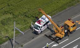 　交差点で乗用車と衝突し、転落した田んぼから引き上げられた救急車＝９日午後０時５７分、三重県鈴鹿市（共同通信社ヘリから）