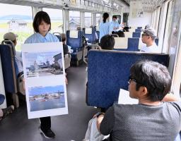 　のと鉄道の「語り部列車」で、津波被害の写真を載せたパネルを乗客に見せる乗務員＝１６日午前（代表撮影）