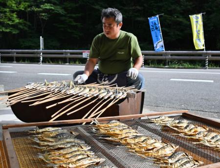 　炭火の上でアユをあぶる木田豪さん＝２５日午後、和歌山県田辺市