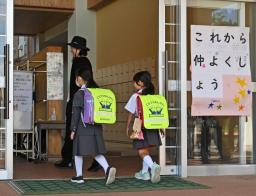 　「これから仲よくしよう」のボードが掲げられた石川県能登町立柳田小に入る輪島市立町野小の児童ら＝１日午前、能登町