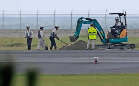 　不発弾の爆発で陥没した宮崎空港の誘導路で作業する関係者＝２日午後５時３９分