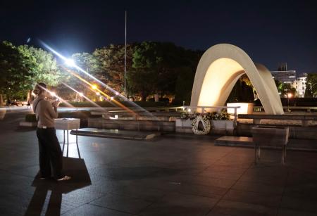 　平和記念公園の原爆慰霊碑を訪れた外国人観光客。被団協のノーベル平和賞受賞が決まった＝１１日午後７時５７分、広島市