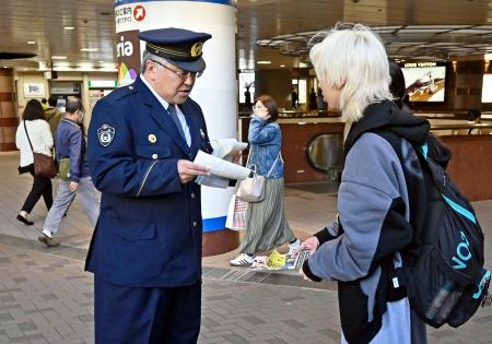 　通行人にチラシを配り、闇バイトへの注意を呼びかける千葉県警の警察官＝１３日午前、千葉市の京成千葉駅前