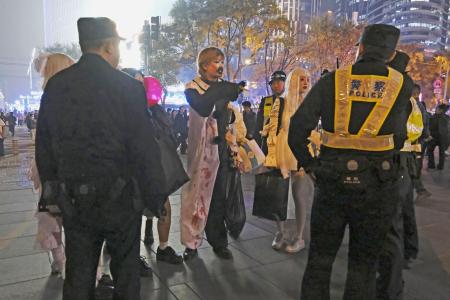 　ハロウィーン期間中、北京市内の繁華街で警察官らに取り囲まれるコスプレした若者＝１０月（共同）