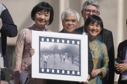 　「ナパーム弾の少女」として知られる写真を持つニック・ウット氏（中央）＝２０２２年５月１１日、バチカン（ＡＰ＝共同）