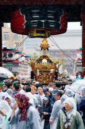 　浅草神社の三社祭で雷門をくぐるみこし。中日の「連合渡御」が行われ、雨の中集まった大勢の見物客を魅了した＝１７日午後、東京都台東区