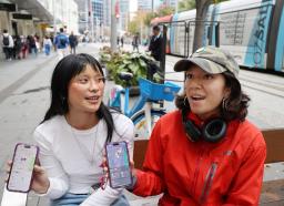 　位置情報共有アプリを使っているシャズさん（左）とヘイゼルさん＝１６日、オーストラリア・シドニー（共同）