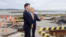 　石川県珠洲市の飯田港で、泉谷満寿裕市長（右）から説明を受ける兵庫県の斎藤元彦知事＝２２日午後