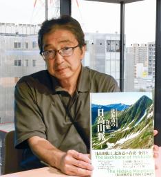 　書籍「北海道の脊梁　日高山脈」を手にする編著者の黒川伸一さん＝５月、札幌市