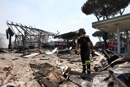 　４日、イタリア・ローマのガソリンスタンドで起きた爆発事故の現場で活動する消防隊員（ロイター＝共同）