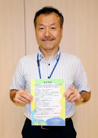 　脱炭素に向けた企業宣言制度のチラシを持つ東京都千代田区の川又孝太郎ゼロカーボン推進技監＝６月、東京都千代田区