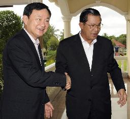 　２００９年、プノンペン近郊カンダル州のフン・セン前首相邸宅で、フン・セン氏（右）と握手するタイのタクシン元首相（ロイター＝共同）