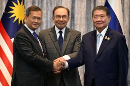 　握手するタイのプムタム首相代行（右）、カンボジアのフン・マネット首相（左）と、仲介したマレーシアのアンワル首相＝７月、クアラルンプール近郊（ロイター＝共同）