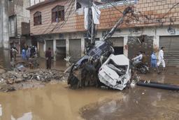 　豪雨による洪水で流され、電柱に衝突した車＝１５日、パキスタン北西部ミンゴラ近郊（ＡＰ＝共同）