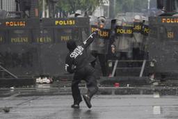 　３１日、インドネシア・ジャカルタの議会付近で警官隊に石を投げつけるデモ参加者（ＡＰ＝共同）