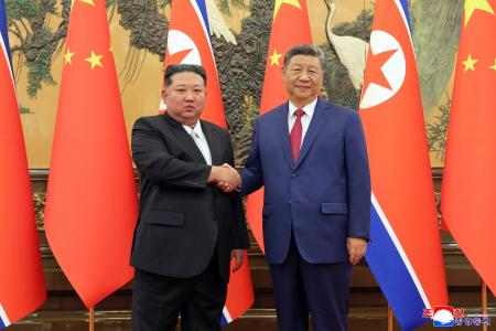 　握手する中国の習近平国家主席（右）と北朝鮮の金正恩朝鮮労働党総書記＝４日、北京（朝鮮中央通信＝共同）