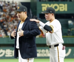 　日米通算２００勝達成を記念するセレモニーで、坂本勇人内野手（右）から受け取った名球会ブレザーを着る巨人・田中将大投手＝１日、東京ドーム