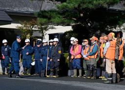 　クマに襲われたとみられる従業員が行方不明になった温泉旅館「瀬美温泉」で、捜索の準備をする警察官と猟友会のメンバー＝１７日午前、岩手県北上市